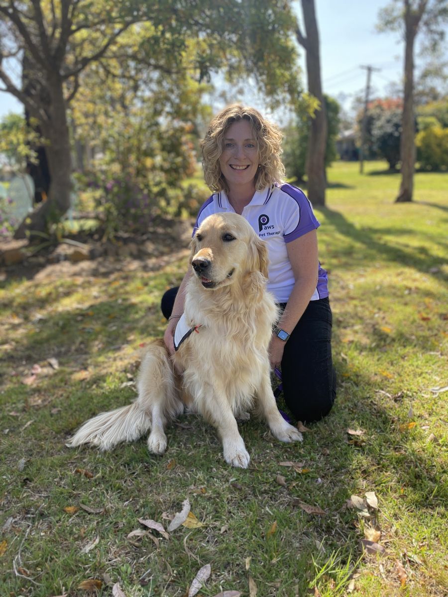 PAWS volunteer Alison kneeling beside Luna, her golden retriever therapy dog